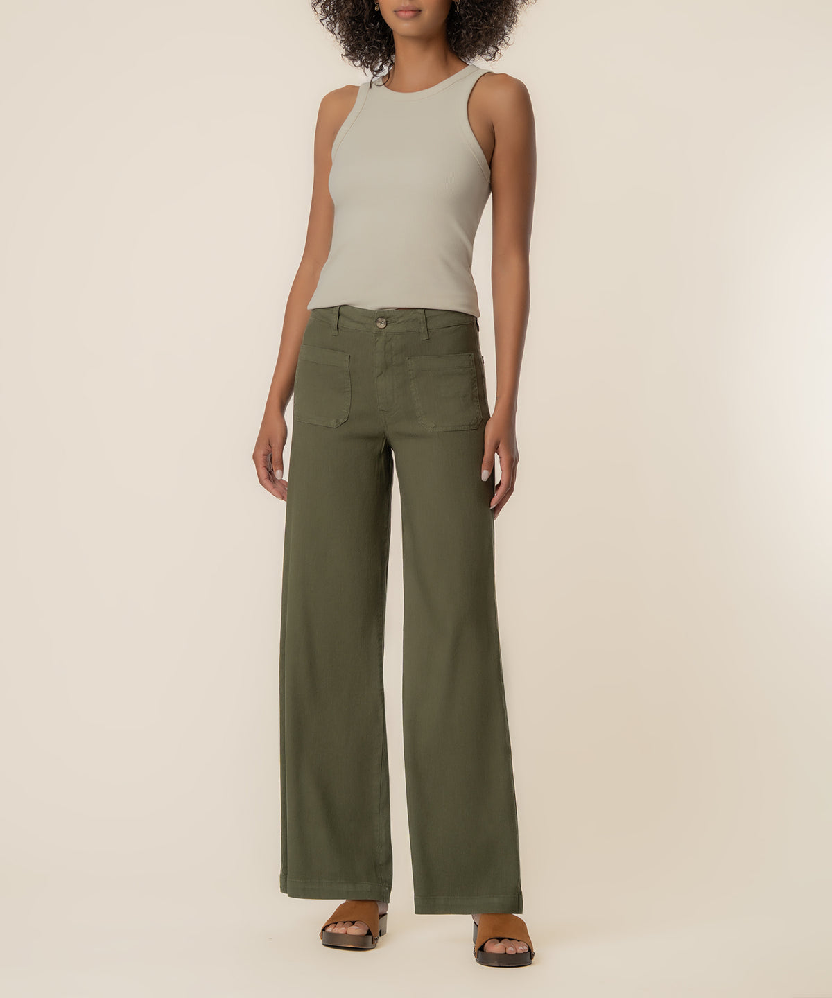 Forest green linen wide-leg pants with high rise waistband and patch pockets, styled with cream tank top.