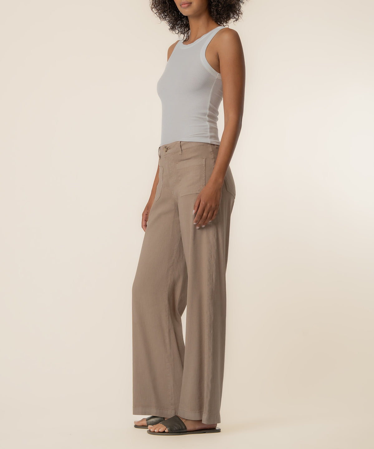 Woman wearing khaki linen high-rise wide-leg pants with a light gray tank top.
