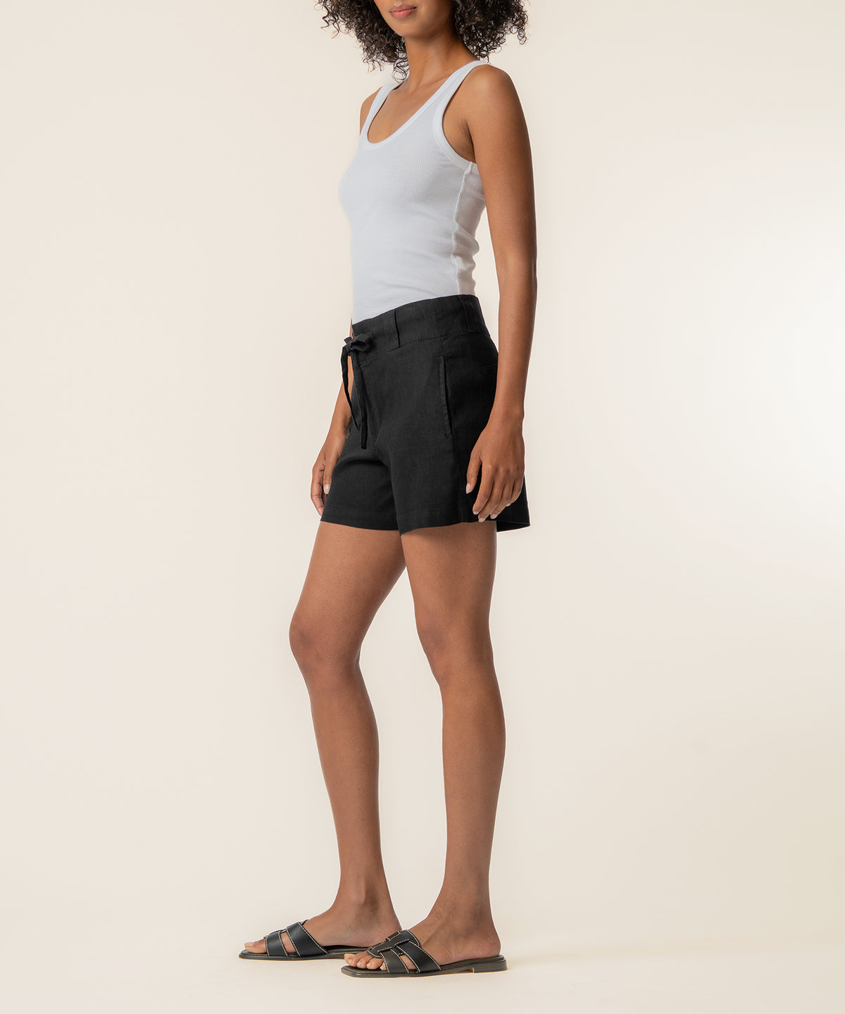 Black linen high-rise shorts with drawstring waist, shown on model wearing white tank top.