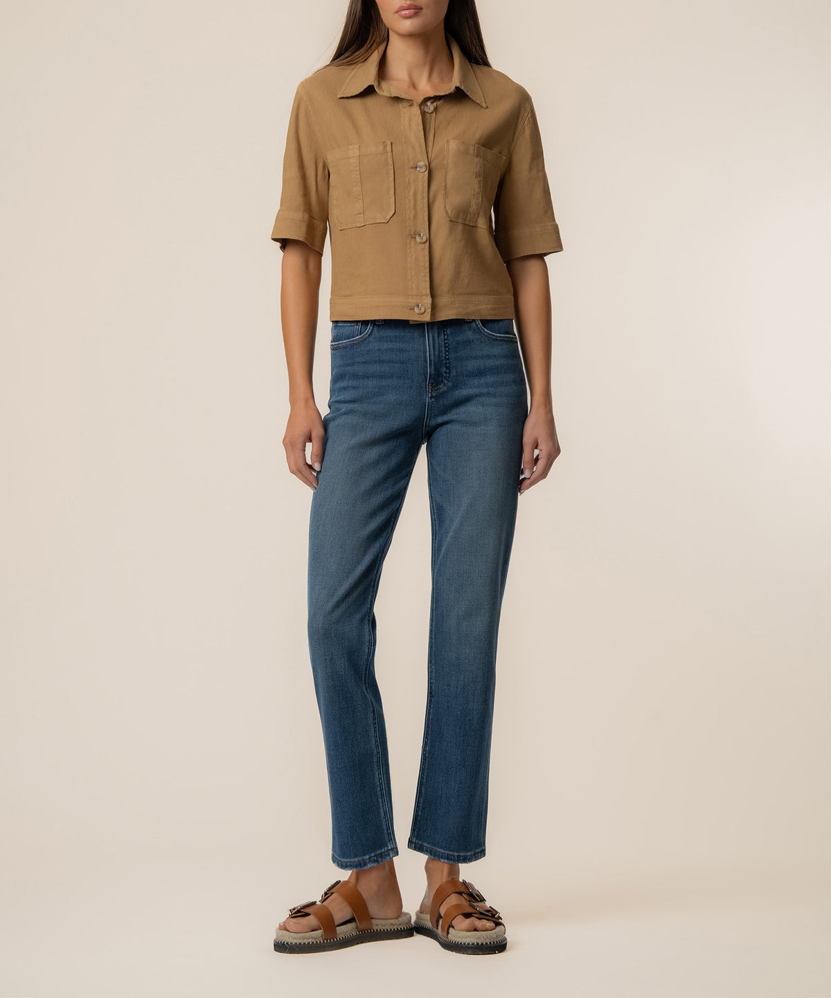 Tan linen jacket with collar, short sleeves, front button closure, and chest pockets worn with blue jeans.