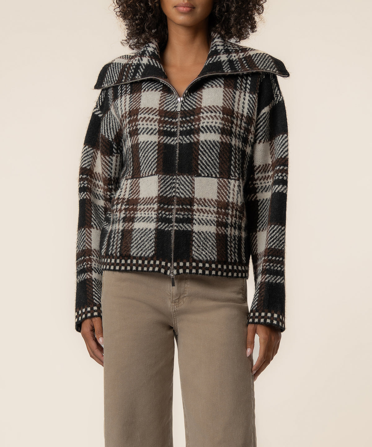 Brown and cream plaid knit jacket with wide collar and zip front on model wearing beige pants.