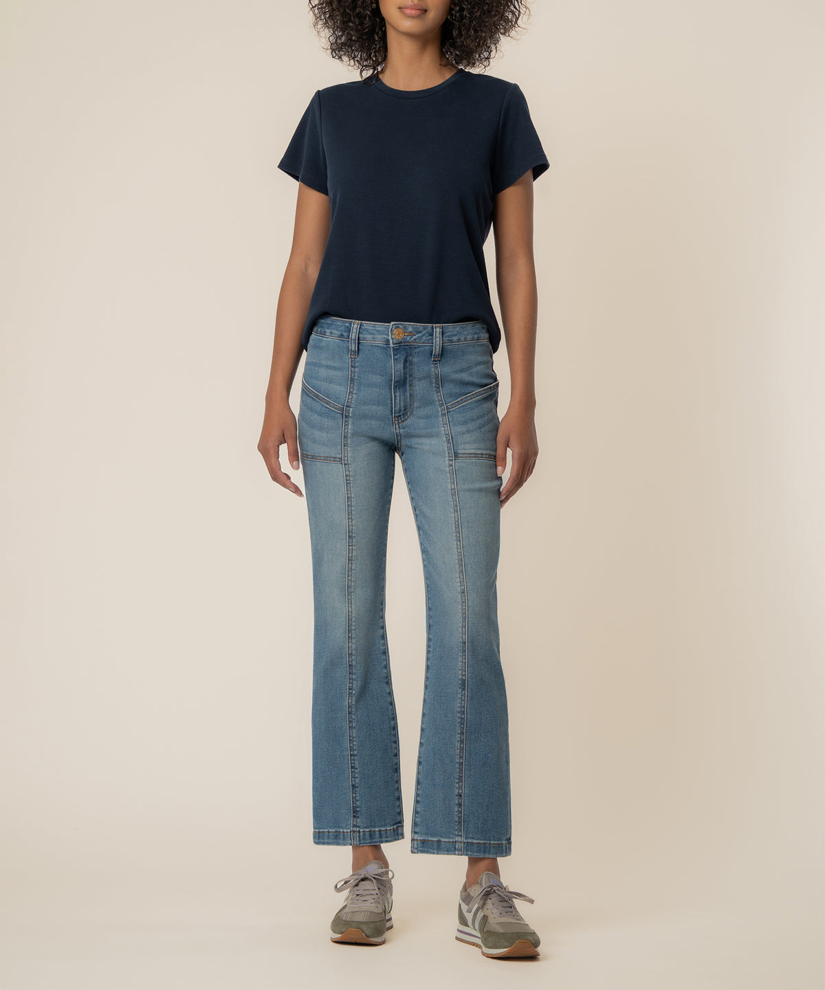 Woman wearing navy short-sleeve t-shirt and light blue high-rise ankle flare jeans with articulated seaming detail.