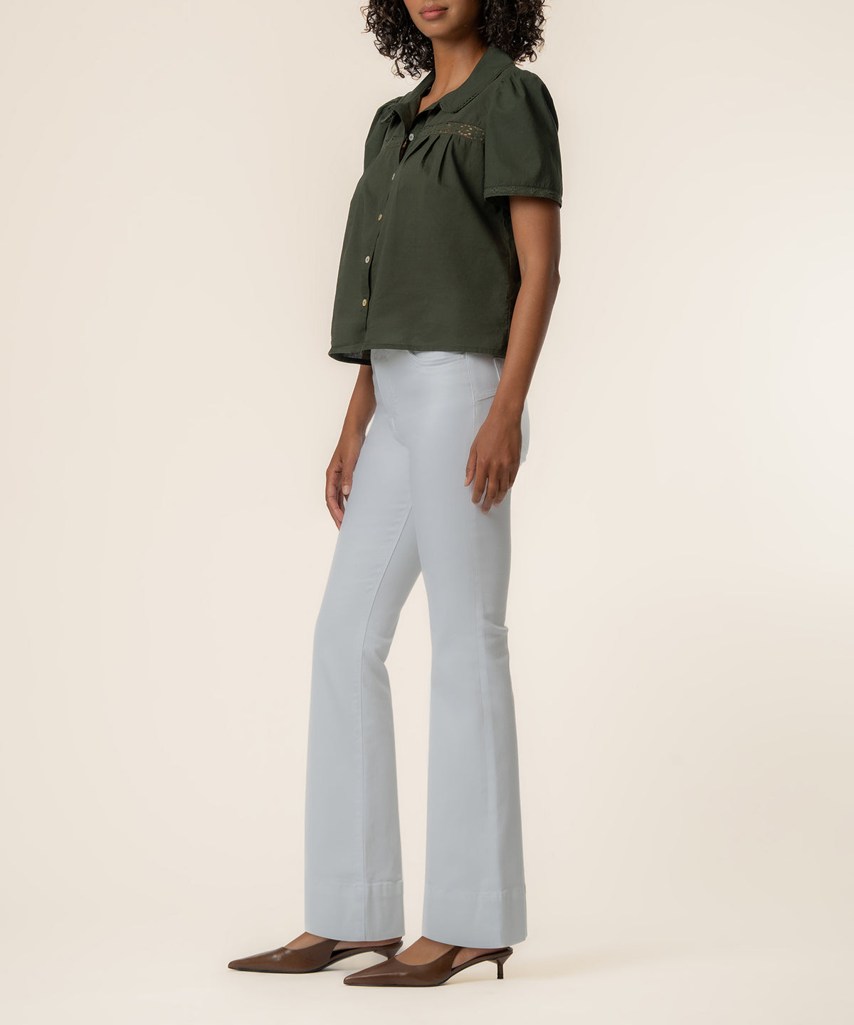 Olive short-sleeve button-front top with collar, worn with light blue flare jeans and brown pointed-toe kitten heels.