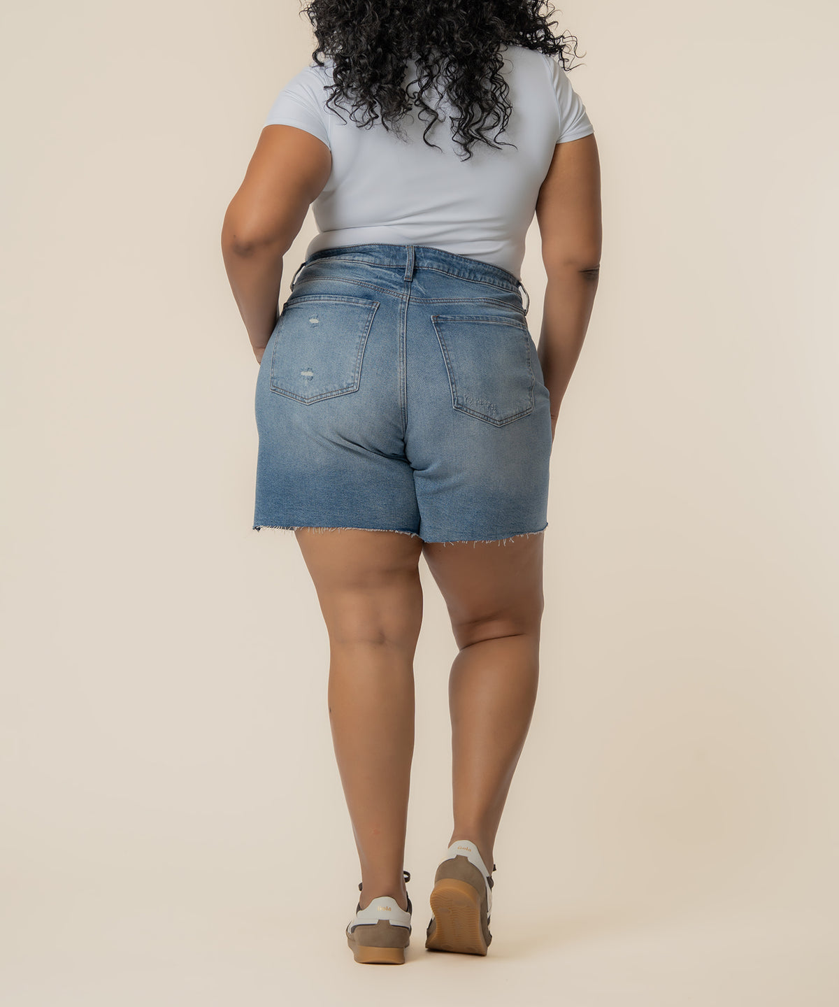 Light blue denim bermuda shorts with frayed hem, high rise waistband, and distressed details on back pockets.