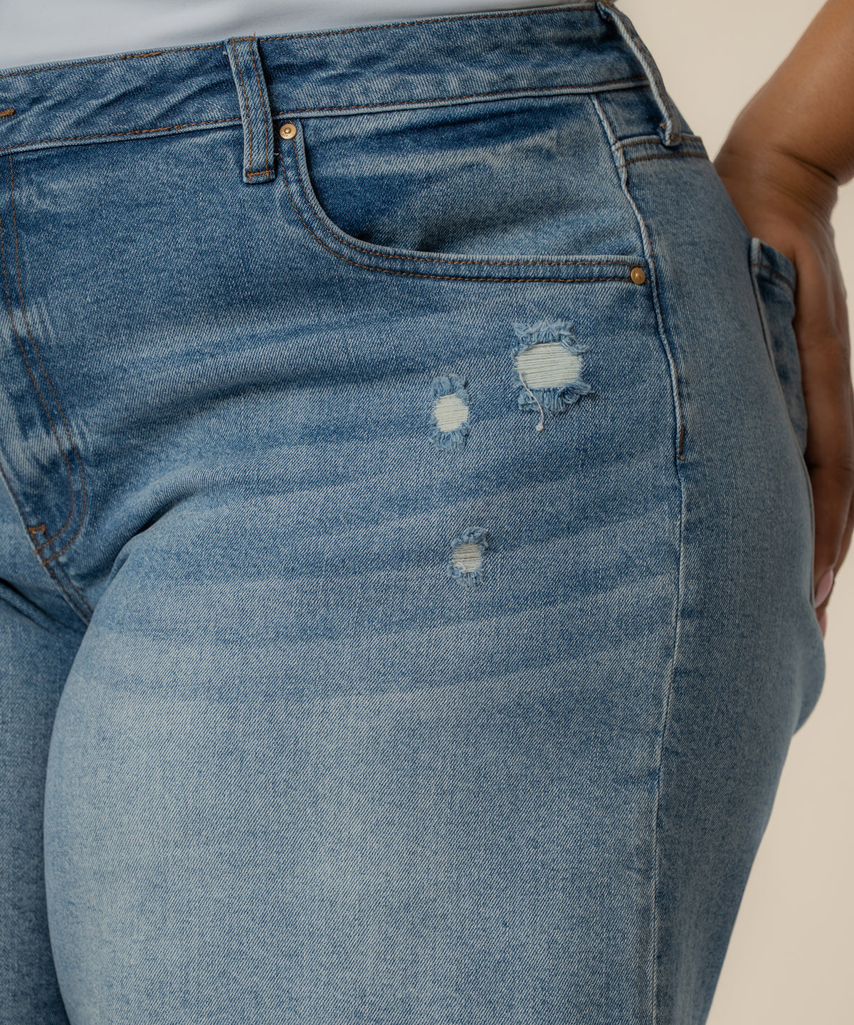 Light blue denim bermuda shorts with distressed rips on thigh, high rise waistband with button closure and front pockets.
