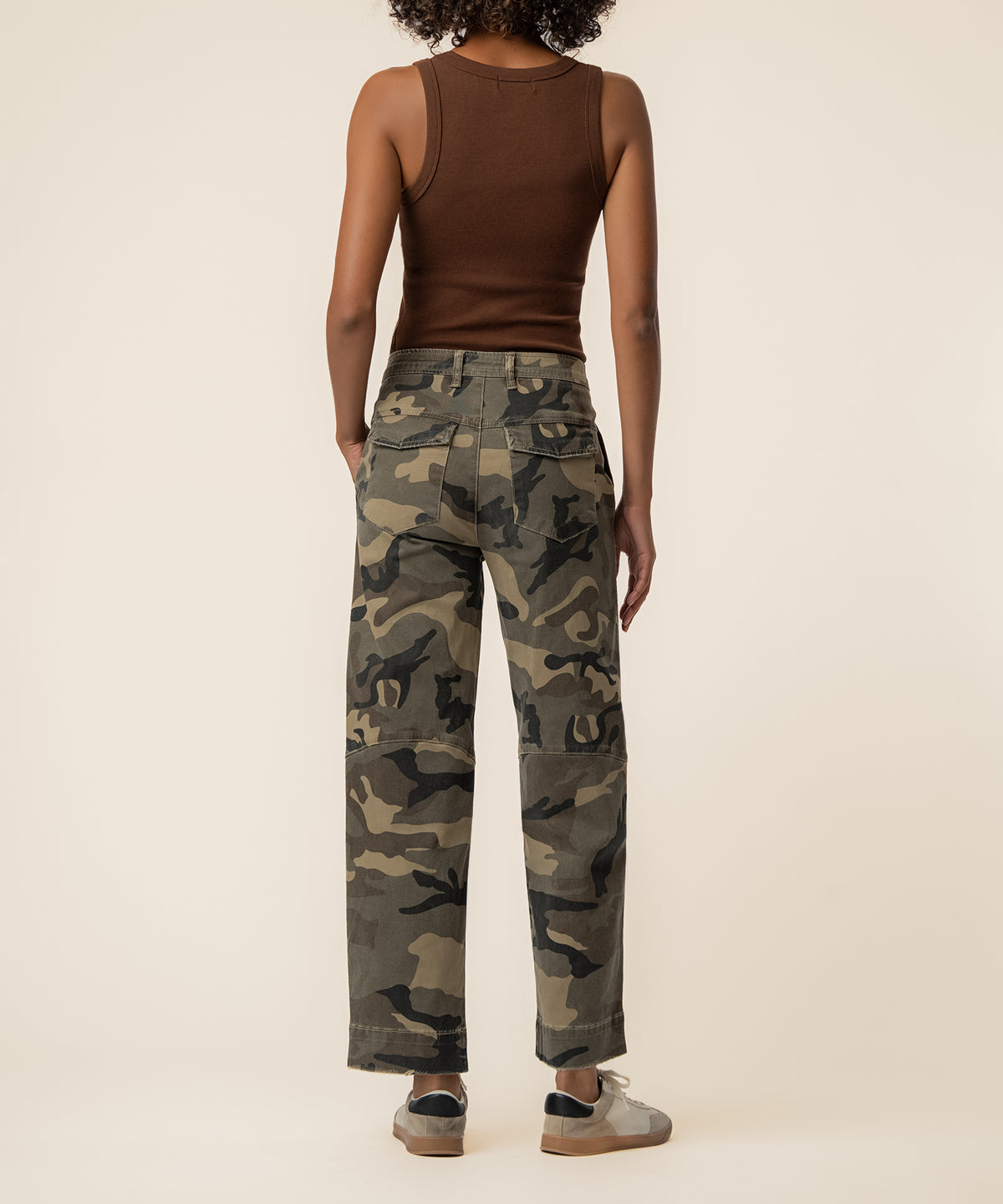 Woman wearing olive camouflage high-rise wide leg jeans with brown sleeveless tank top, back view.