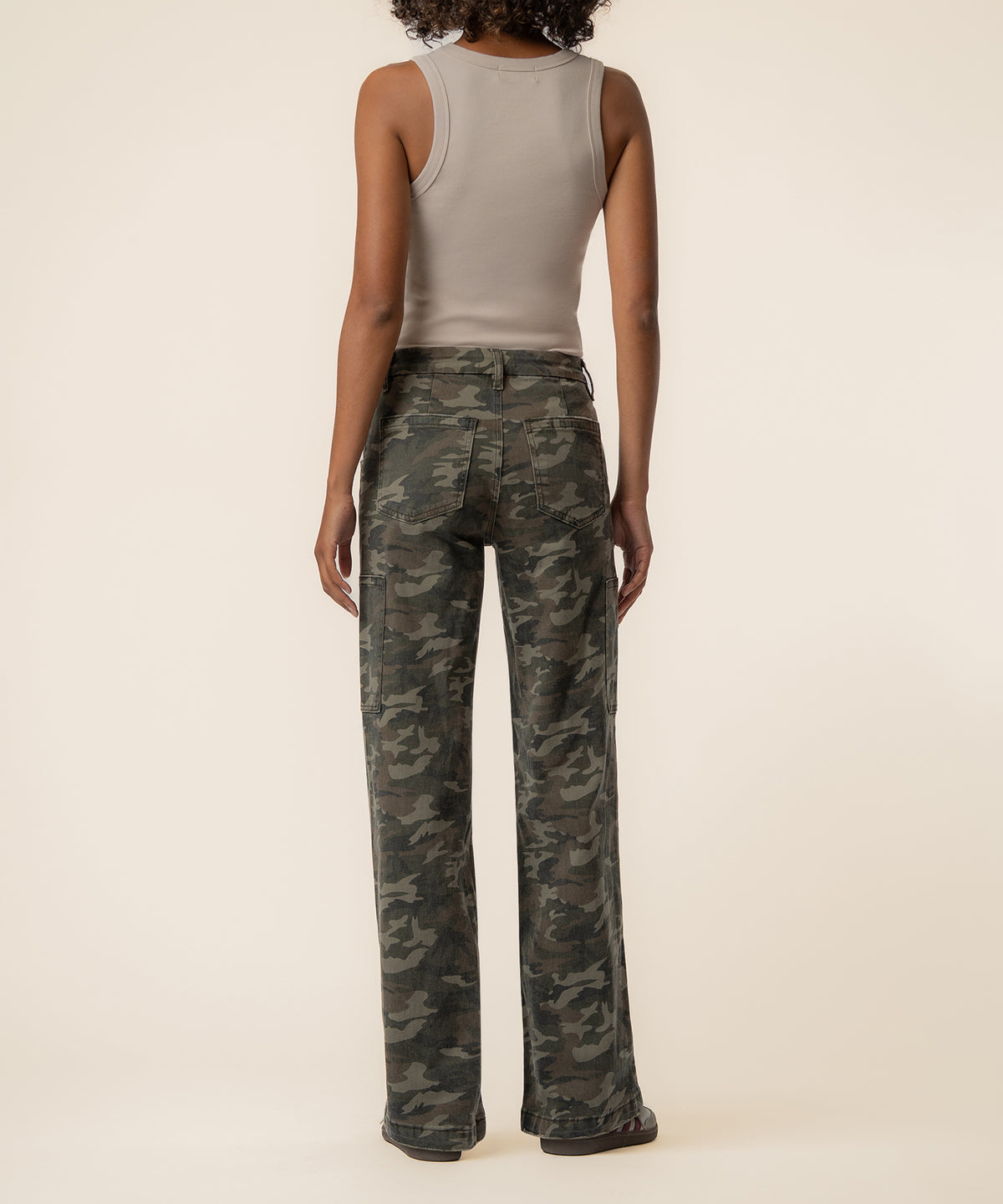 Olive camouflage high-rise wide-leg jeans with straight silhouette, shown from back on model wearing beige tank top.