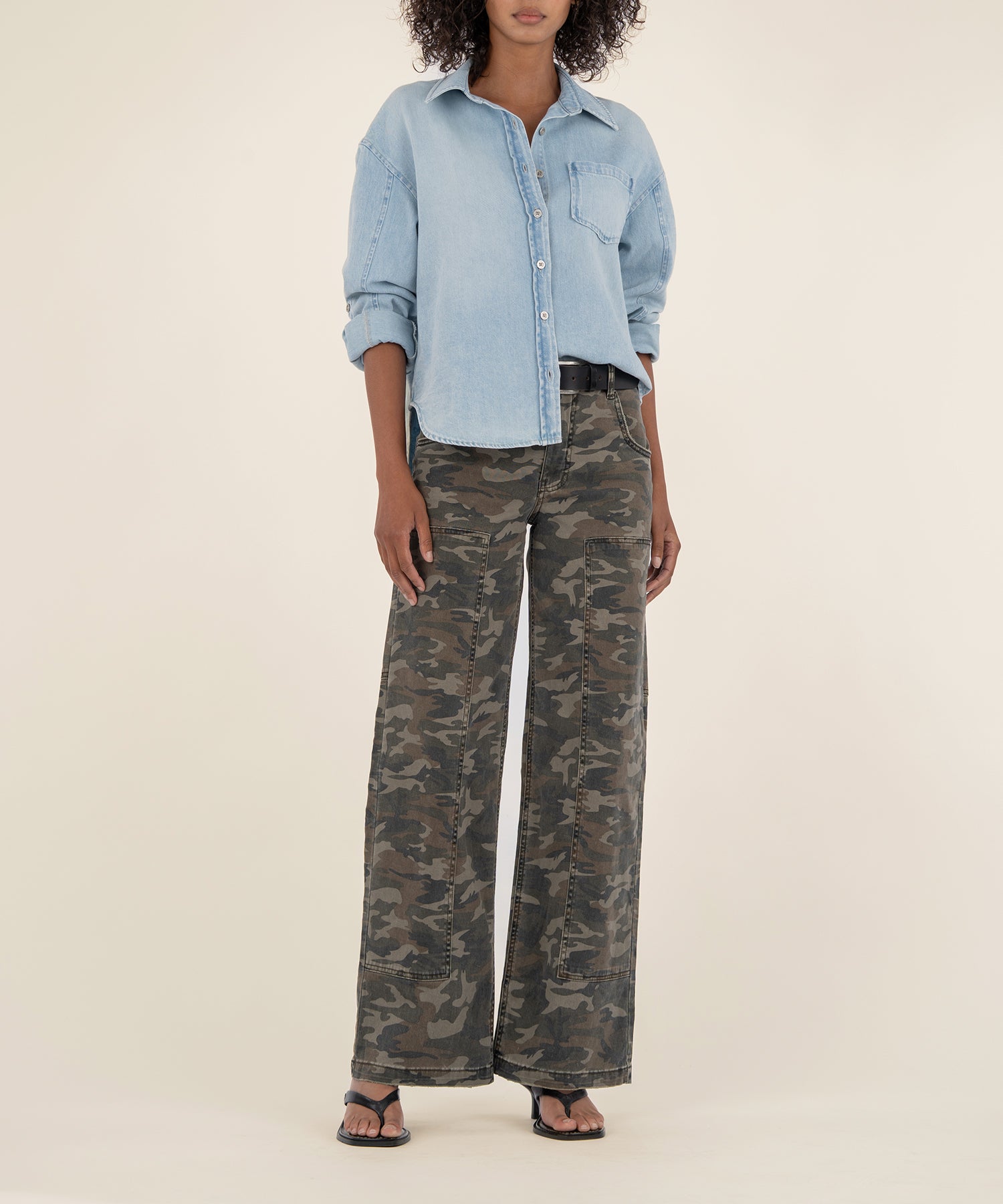 Camouflage print wide-leg jeans with high rise waistband in olive tones, styled with light blue denim shirt.