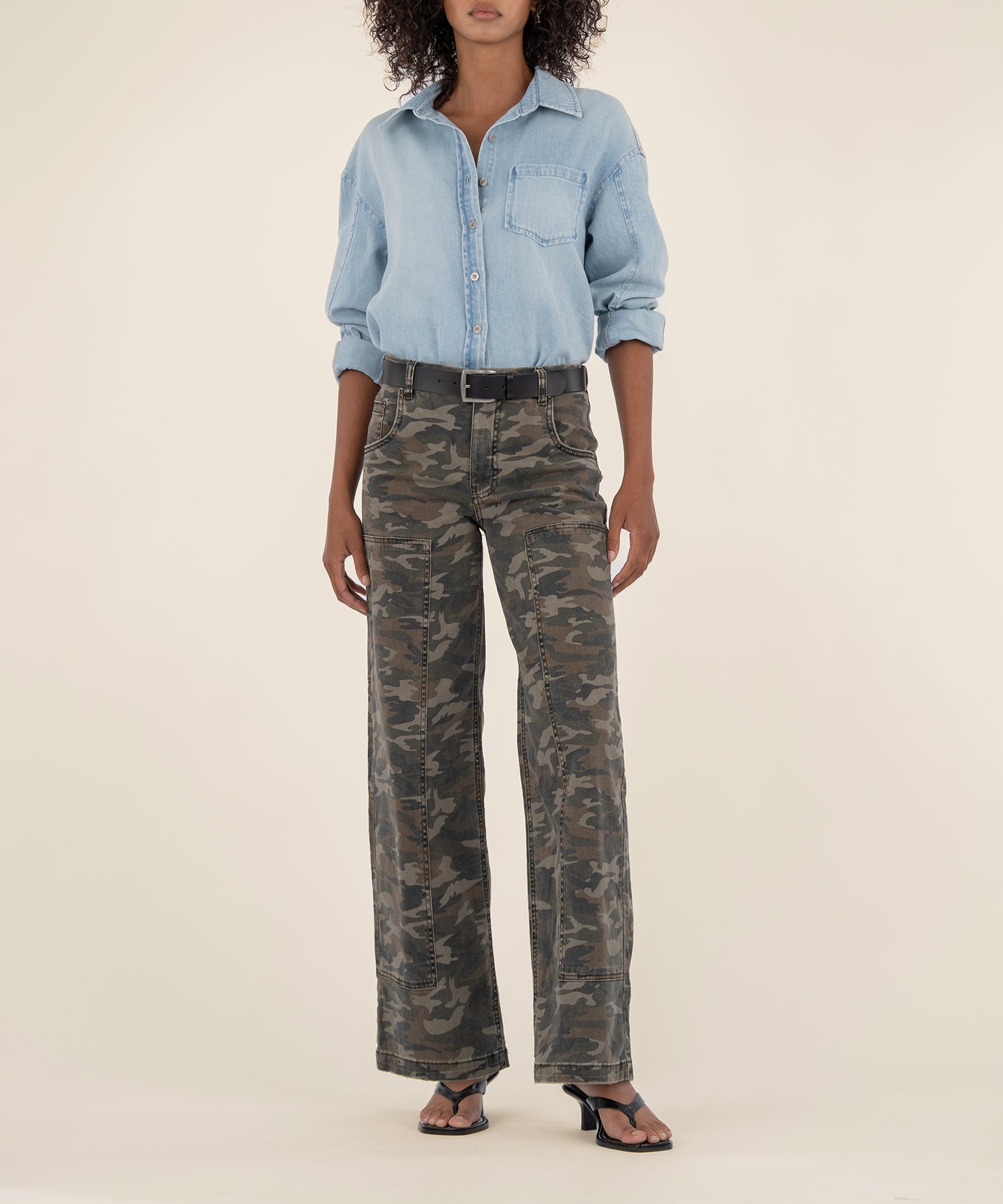 Olive camouflage high-rise wide-leg jeans with cargo pockets and belt loops, styled with light blue denim shirt.
