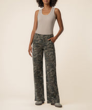 Olive camouflage high-rise wide-leg jeans with cargo pockets, styled with a beige tank top.