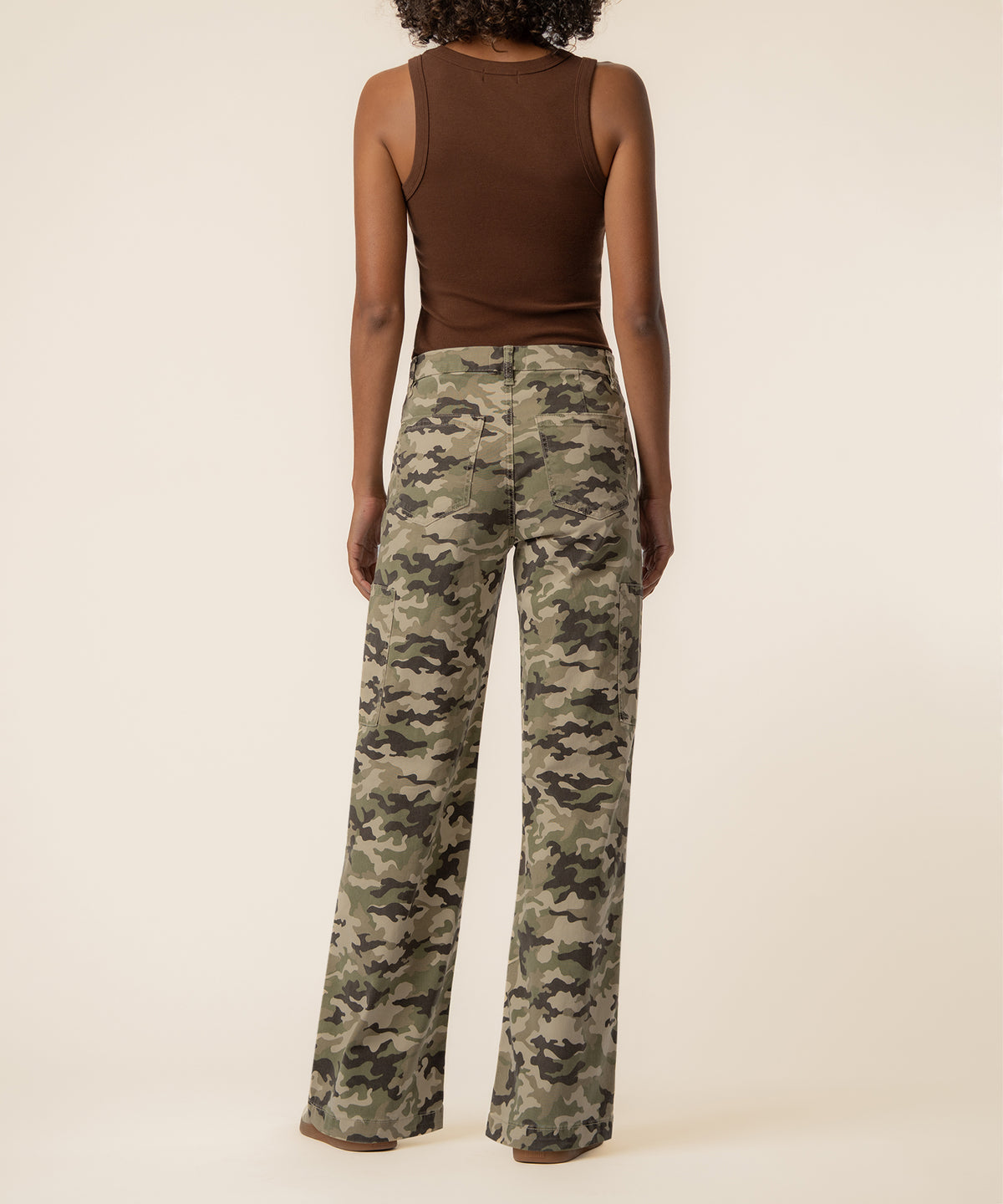 Person wearing brown sleeveless top and olive camouflage wide-leg jeans with high rise waistband, back view.