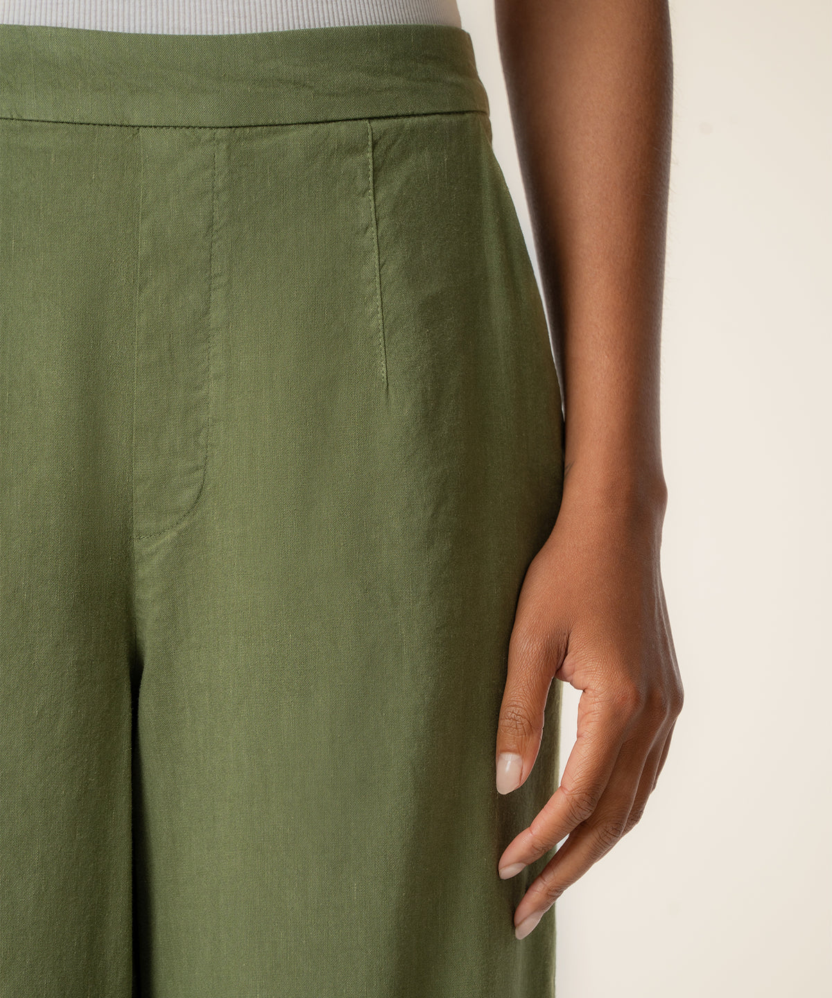 Dill-colored linen high-rise wide-leg pants shown from waist to knee on model wearing white ribbed top.