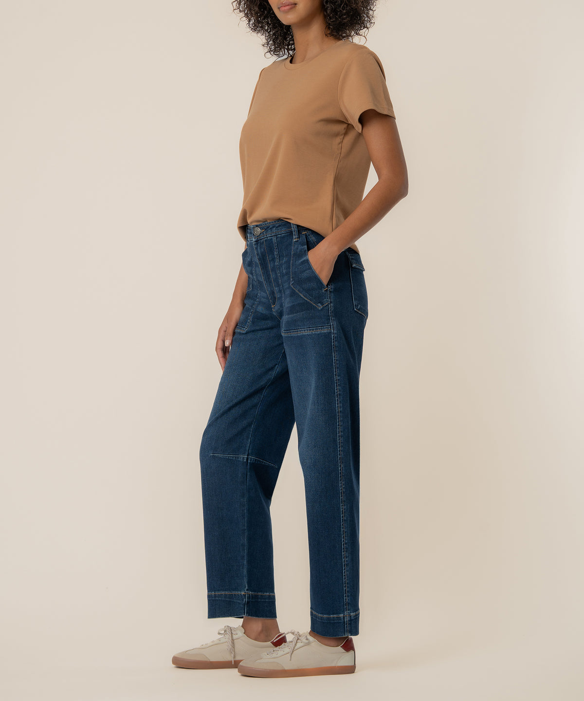 Woman wearing dark wash wide leg barrel jeans with cuffed ankles and side pockets, paired with a tan t-shirt.