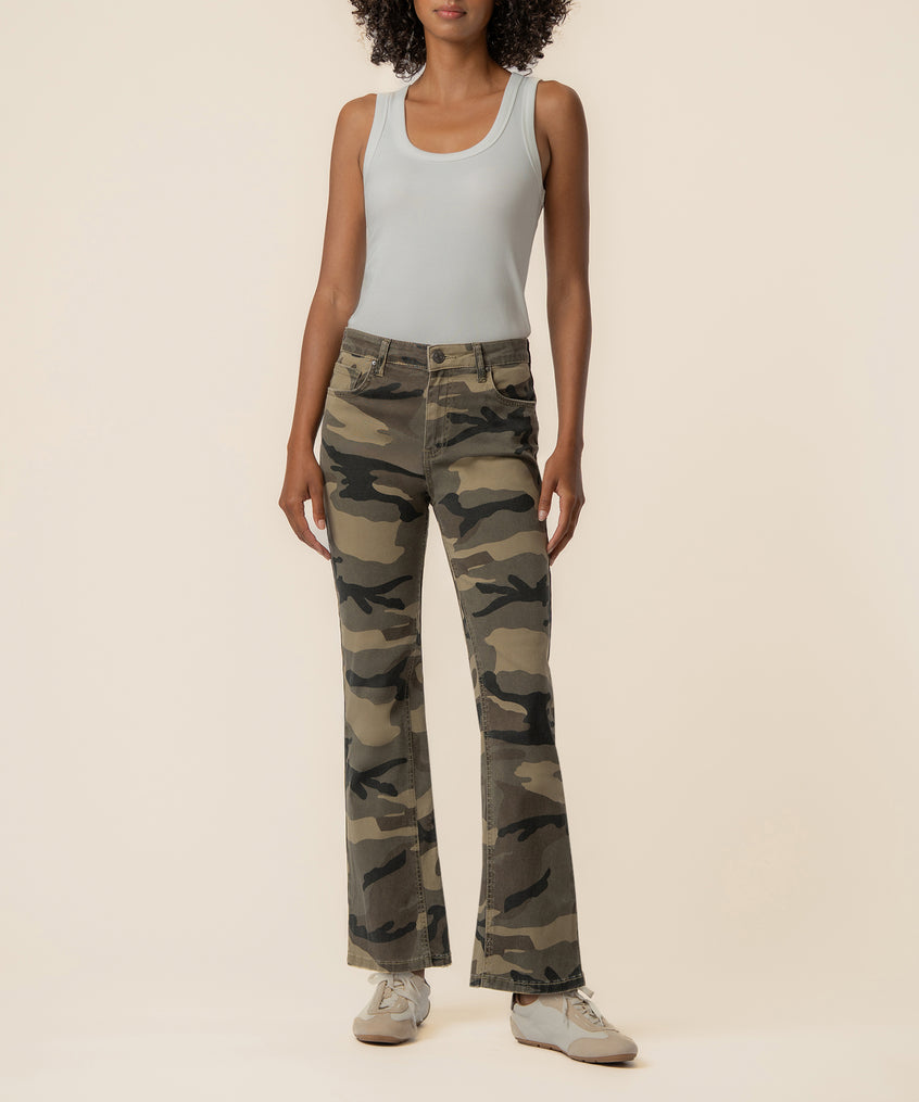 Olive camouflage high-rise ankle flare jeans with flared legs, worn with white tank top and sneakers.