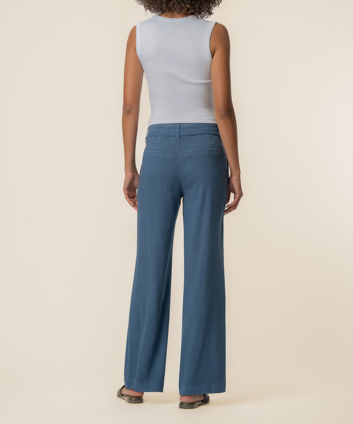 Coastal blue linen wide leg pants worn with light blue sleeveless top, shown from back view.