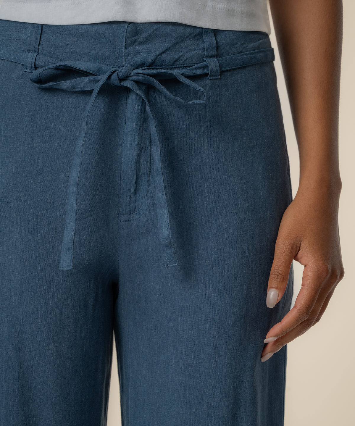 Blue linen wide-leg pants with tie waist detail at the hip.