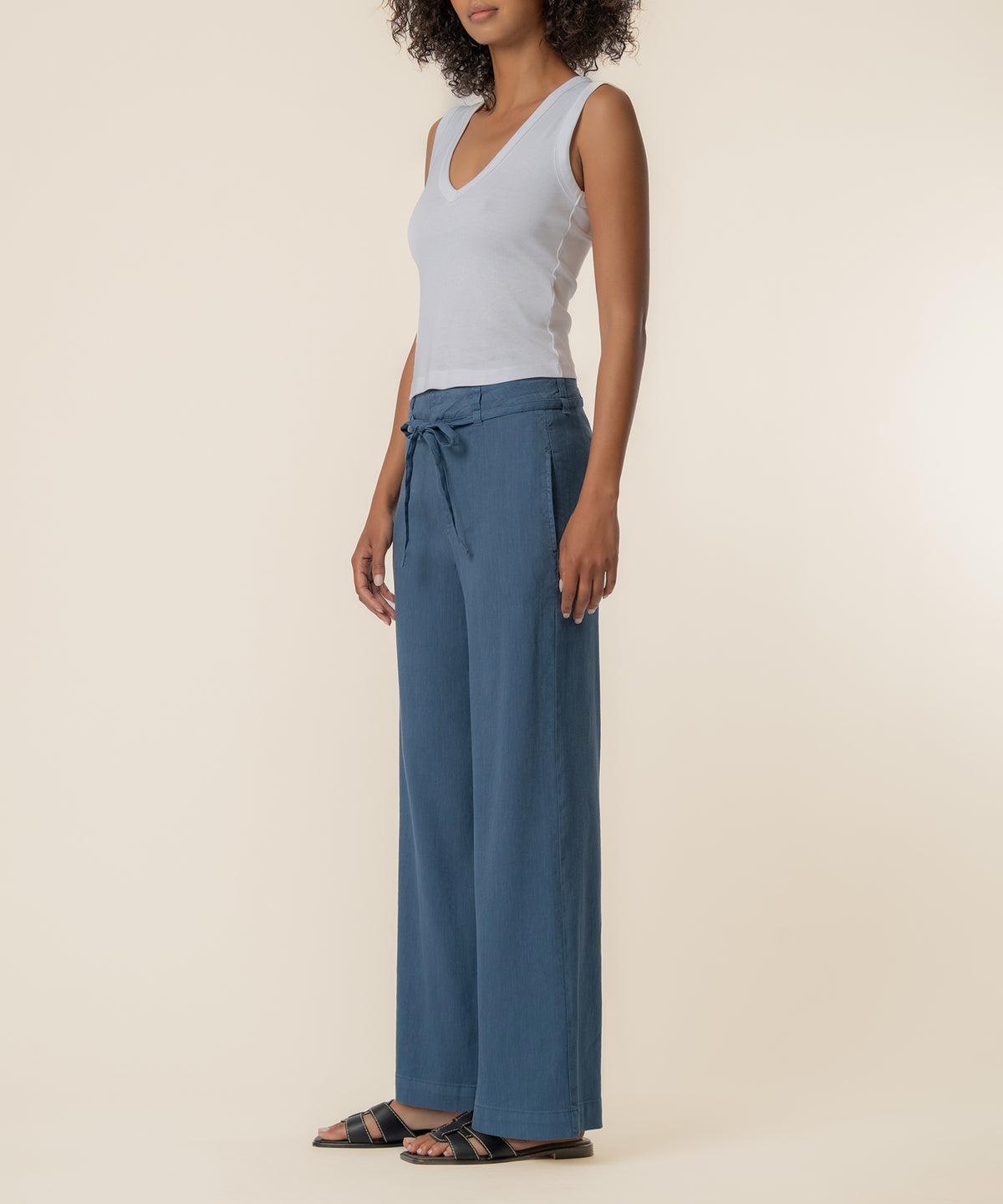 Woman wearing a blue linen wide-leg pant with a drawstring waist and white sleeveless top.