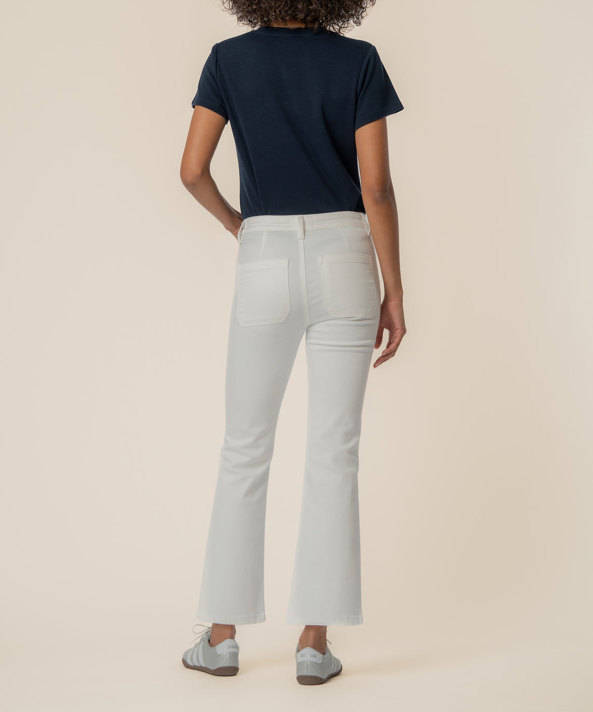 White high-rise flare jeans with back pockets, shown from behind with navy t-shirt.