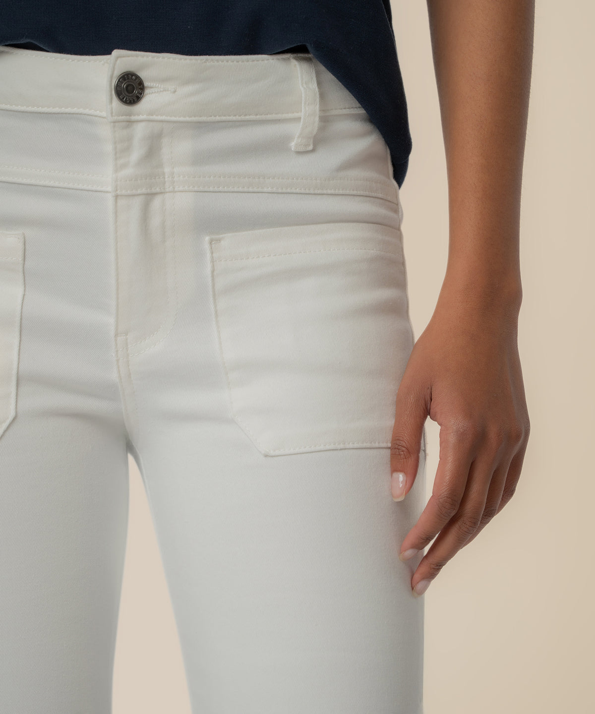 White high-rise flare jeans with button closure and patch pockets, worn with navy top.