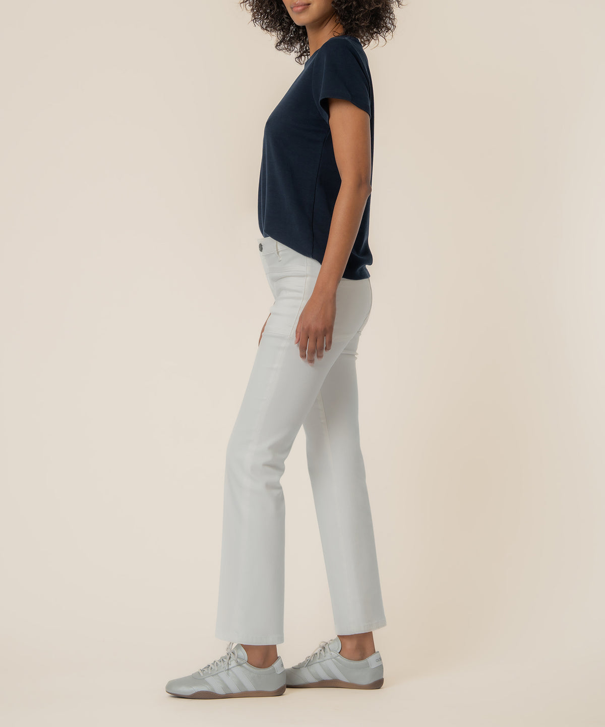 White high-rise flare jeans with a cropped length, worn with a navy short-sleeve top.