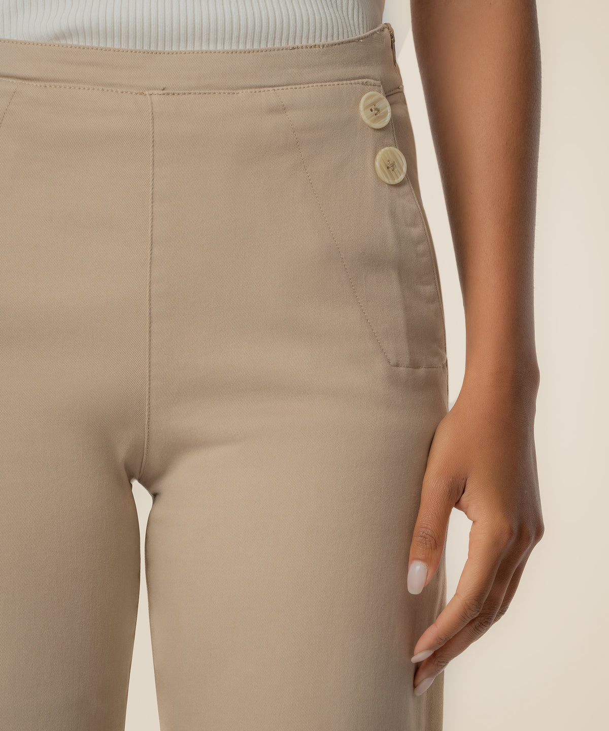 Sand-colored high rise wide leg pant with button side closure detail and vertical seaming.