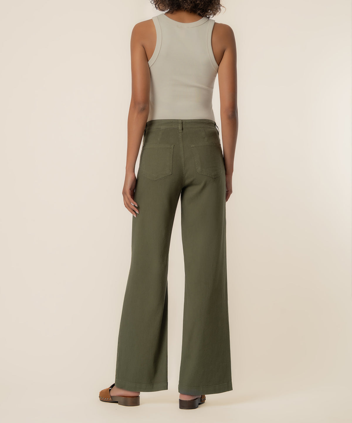 Forest green high-rise wide-leg linen pants with back pockets, shown from behind on model wearing cream tank top.