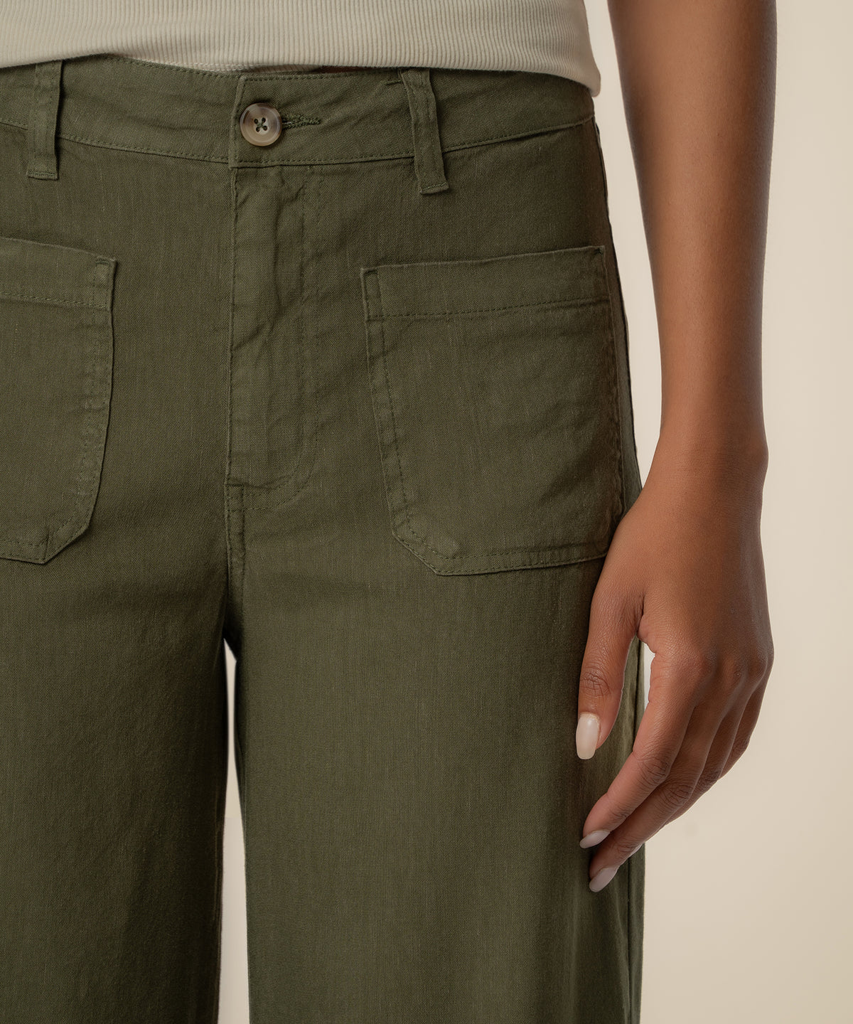 Forest green linen high-rise wide-leg pants with front patch pockets and button closure.