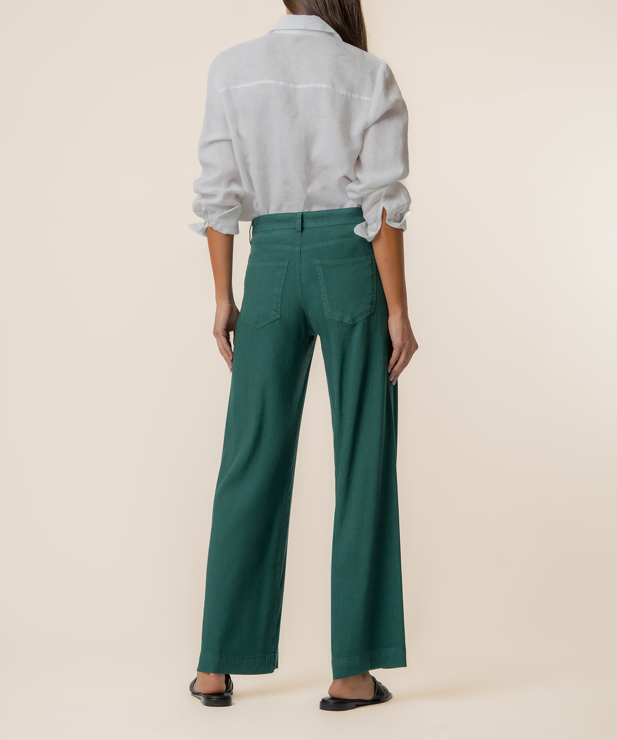 Woman wearing white linen shirt and high-rise wide-leg jungle green pants, back view.