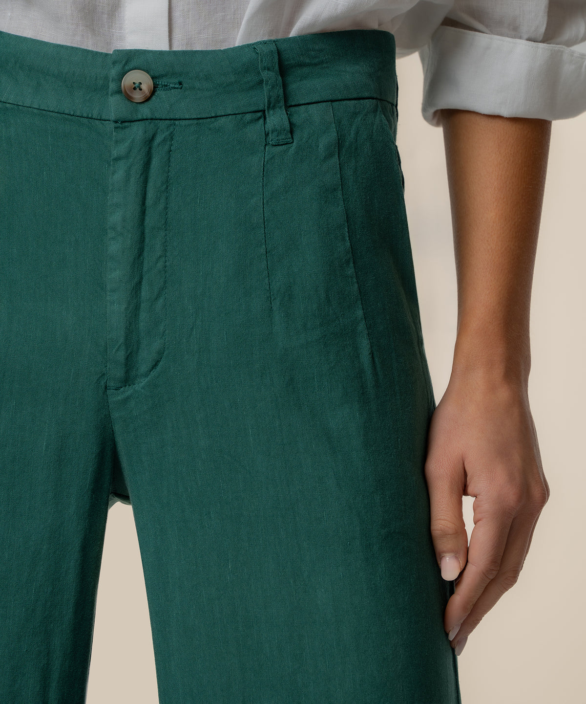 Dark green linen high-rise wide-leg pants with button closure, shown with white linen shirt.