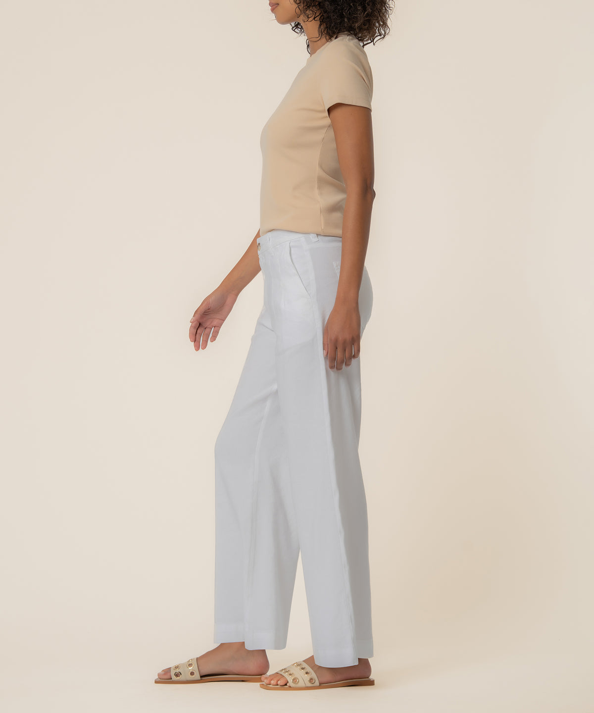 Woman wearing white linen high-rise wide-leg pants with a beige short-sleeve top and tan slide sandals.