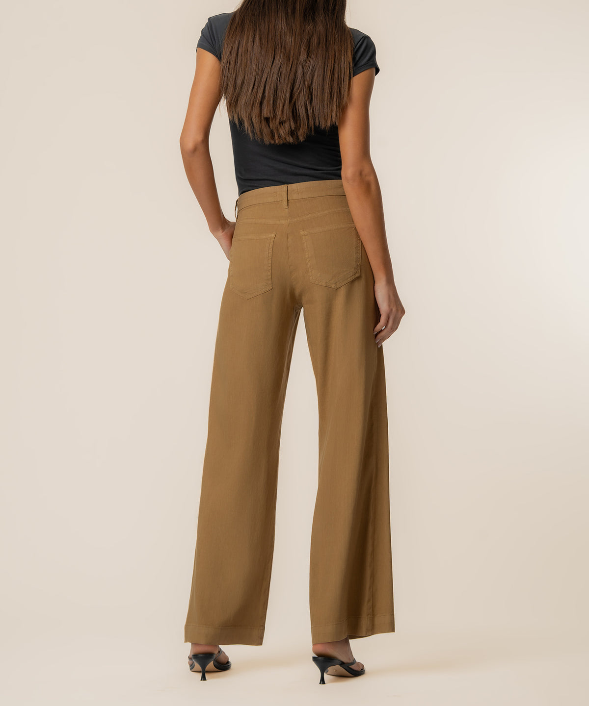 Woman wearing tan linen high-rise wide-leg straight pants with black short-sleeve top, shown from back.