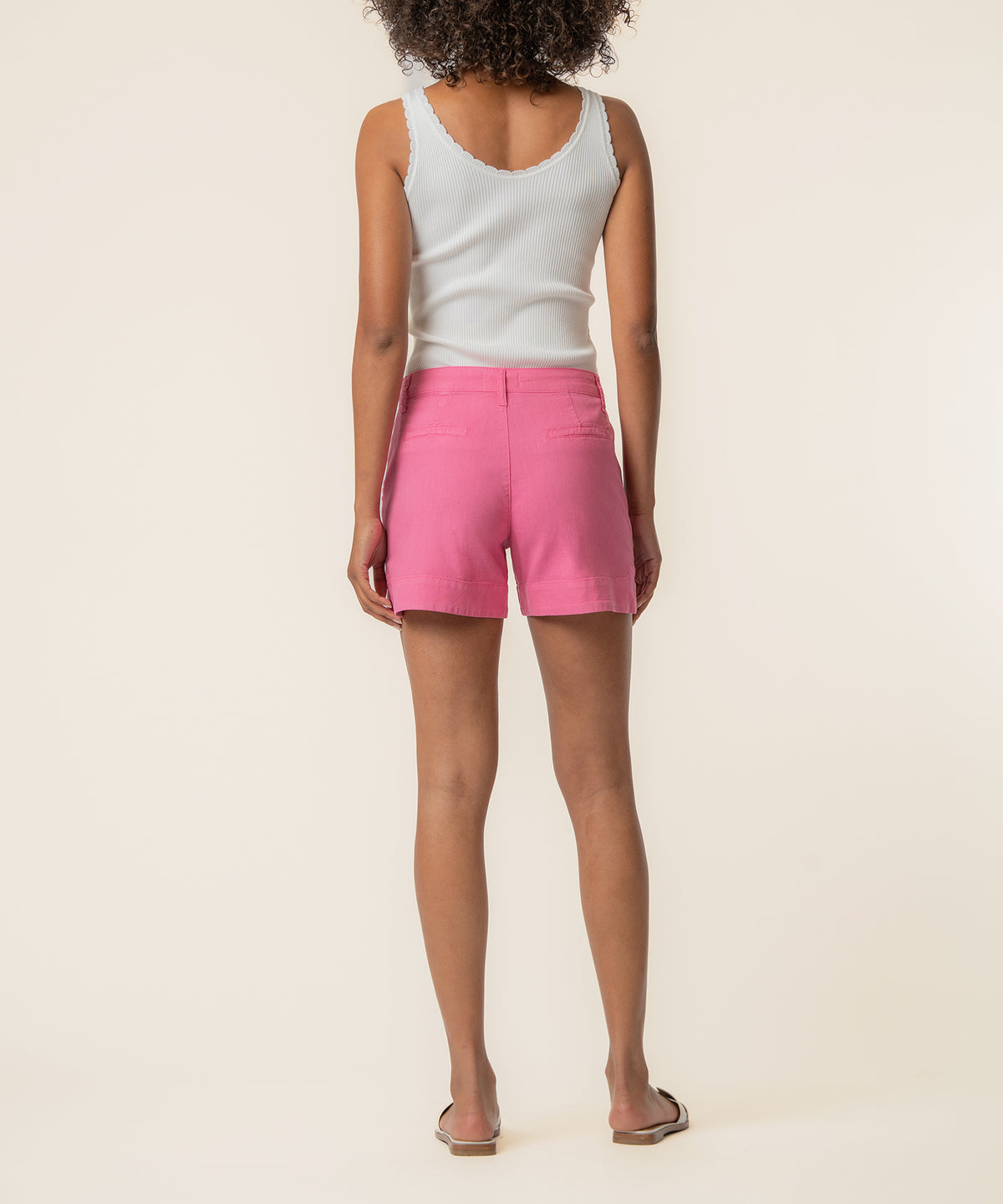 Lipstick pink linen high-rise shorts on model wearing white tank top, back view.
