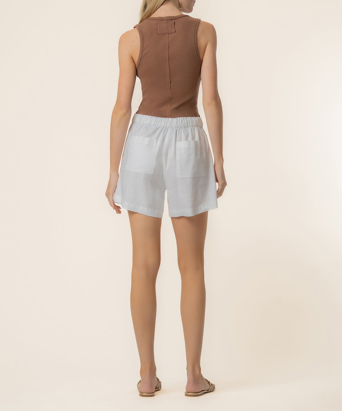 White linen shorts with high rise waistband and patch pockets, shown from back view.