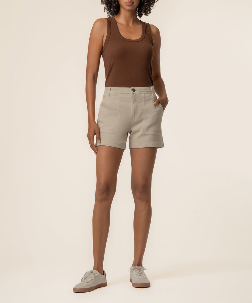 Woman wearing brown tank top and beige high-rise shorts with front pockets and button closure.