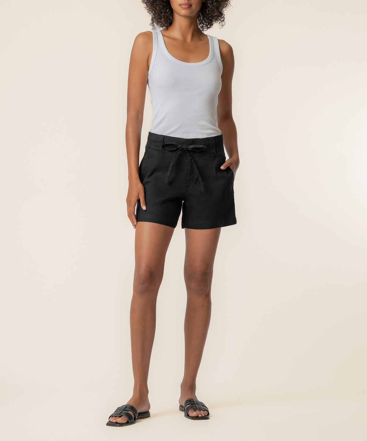 Black linen high-rise shorts with drawstring waist and side pockets, paired with white tank top.
