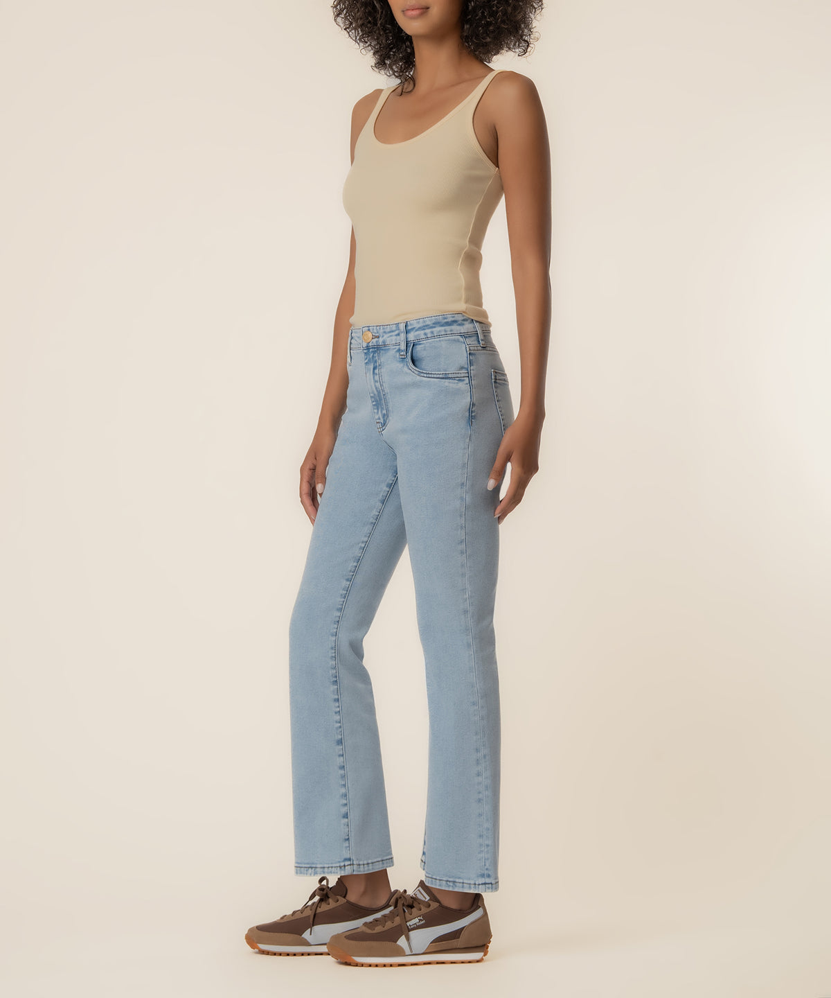 Light blue high-rise ankle flare jeans with a slight wash, paired with a cream tank top and brown sneakers.