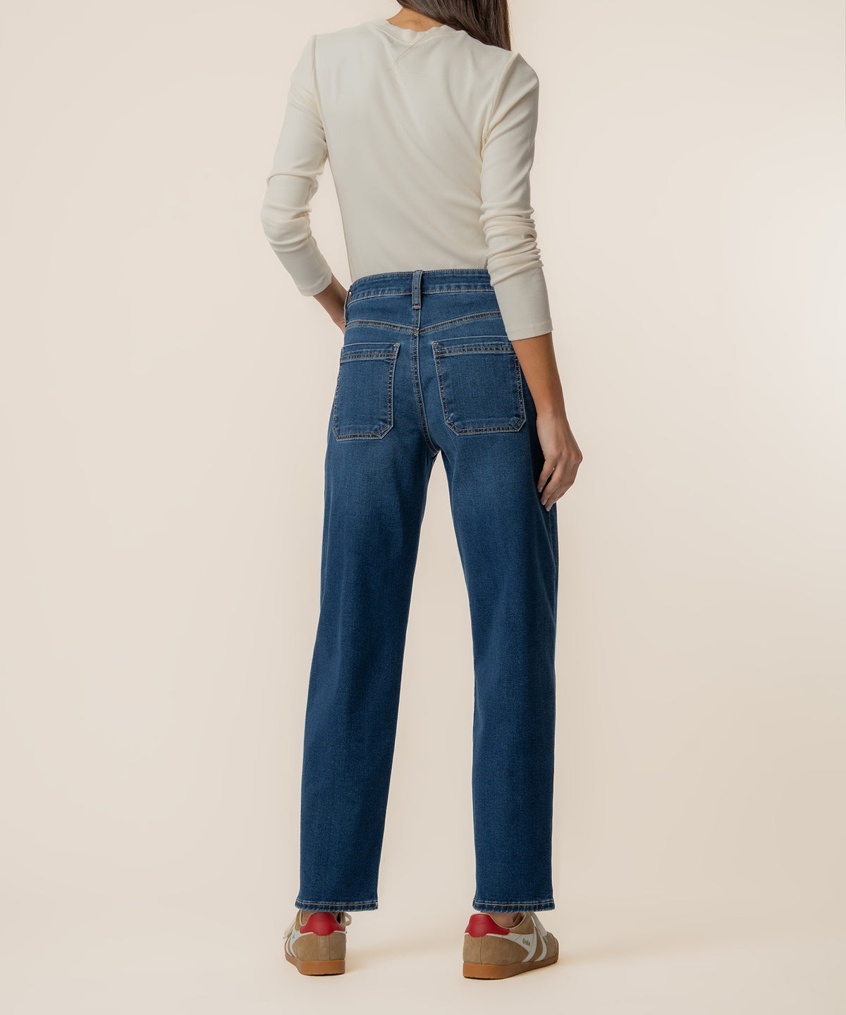 Woman wearing high-rise wide-leg blue jeans with a cream long-sleeve top, shown from behind.
