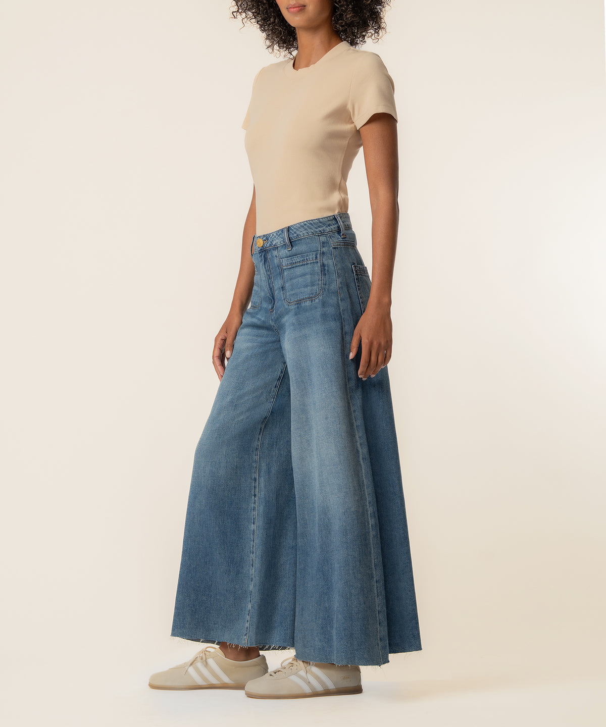 Woman wearing beige short-sleeve t-shirt and wide-leg blue denim crop jeans with raw hem.
