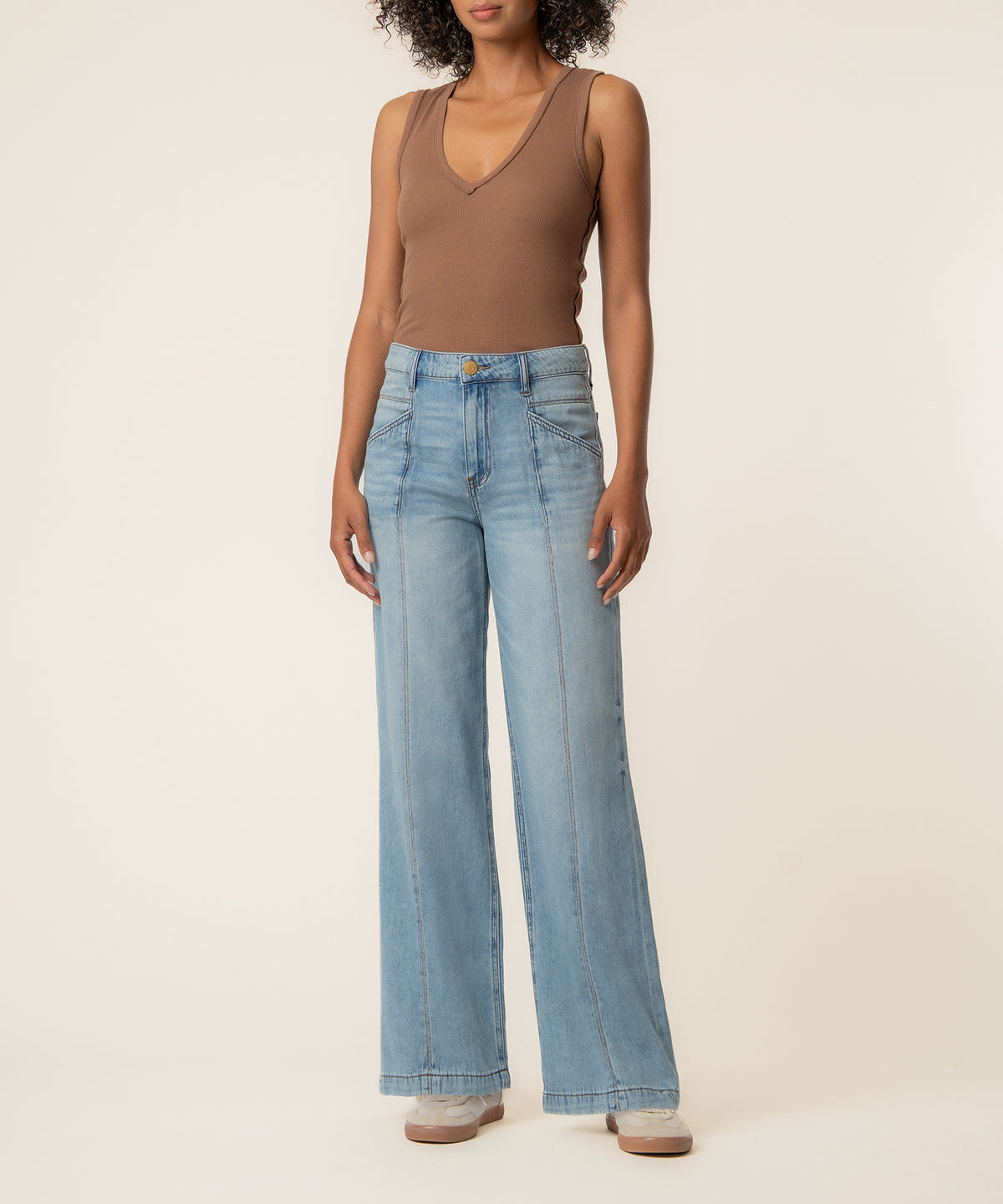 Woman wearing a taupe sleeveless tank top and light blue high-rise wide-leg jeans with a relaxed fit.