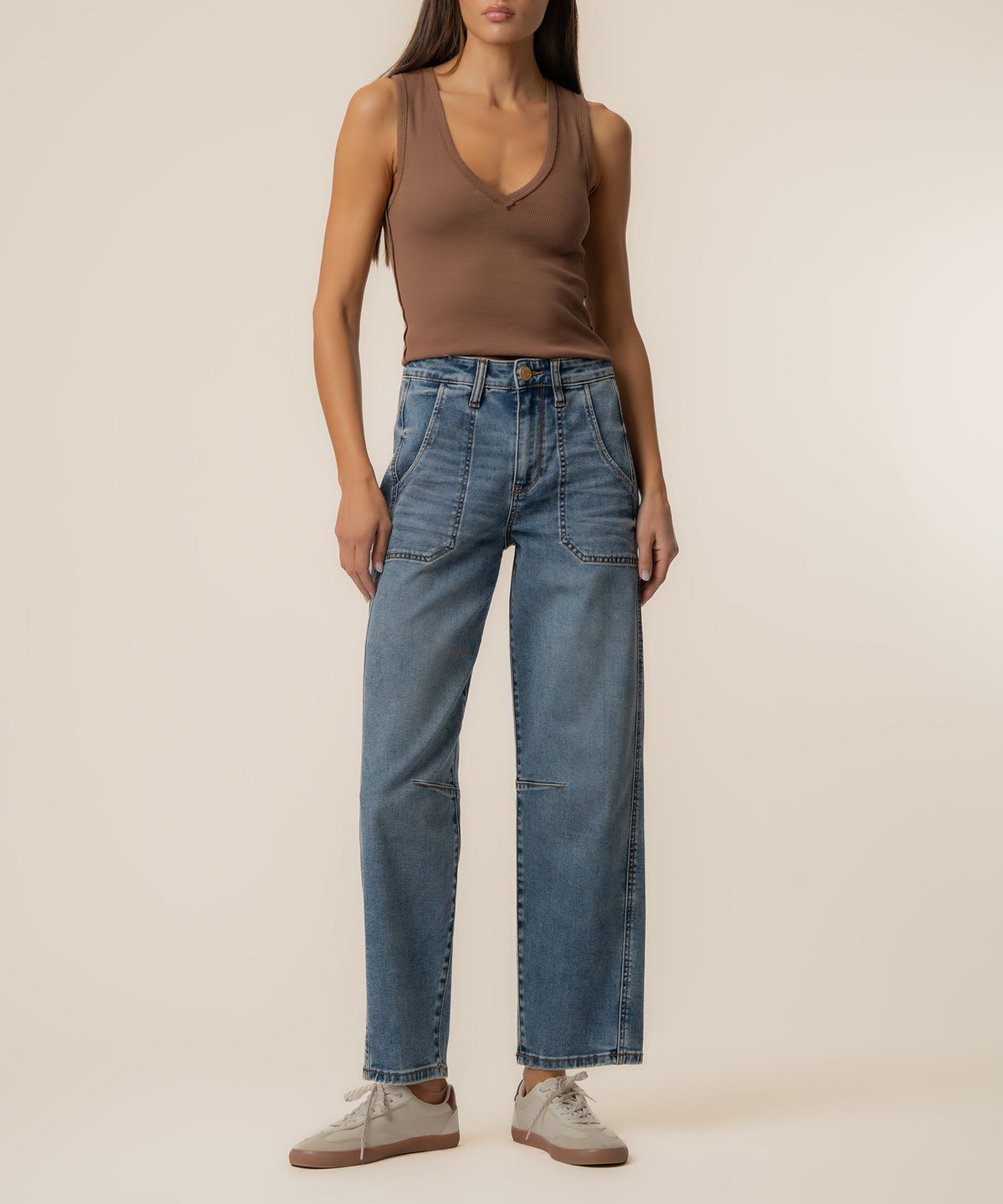 Woman wearing high-rise wide-leg blue jeans with visible seam details and a brown sleeveless top.
