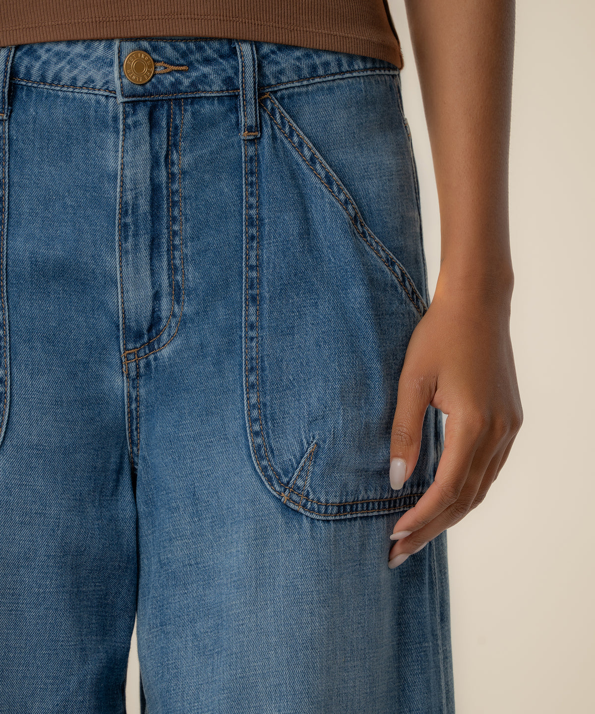 High-rise wide-leg jeans in medium blue wash with gold button and stitched pockets.