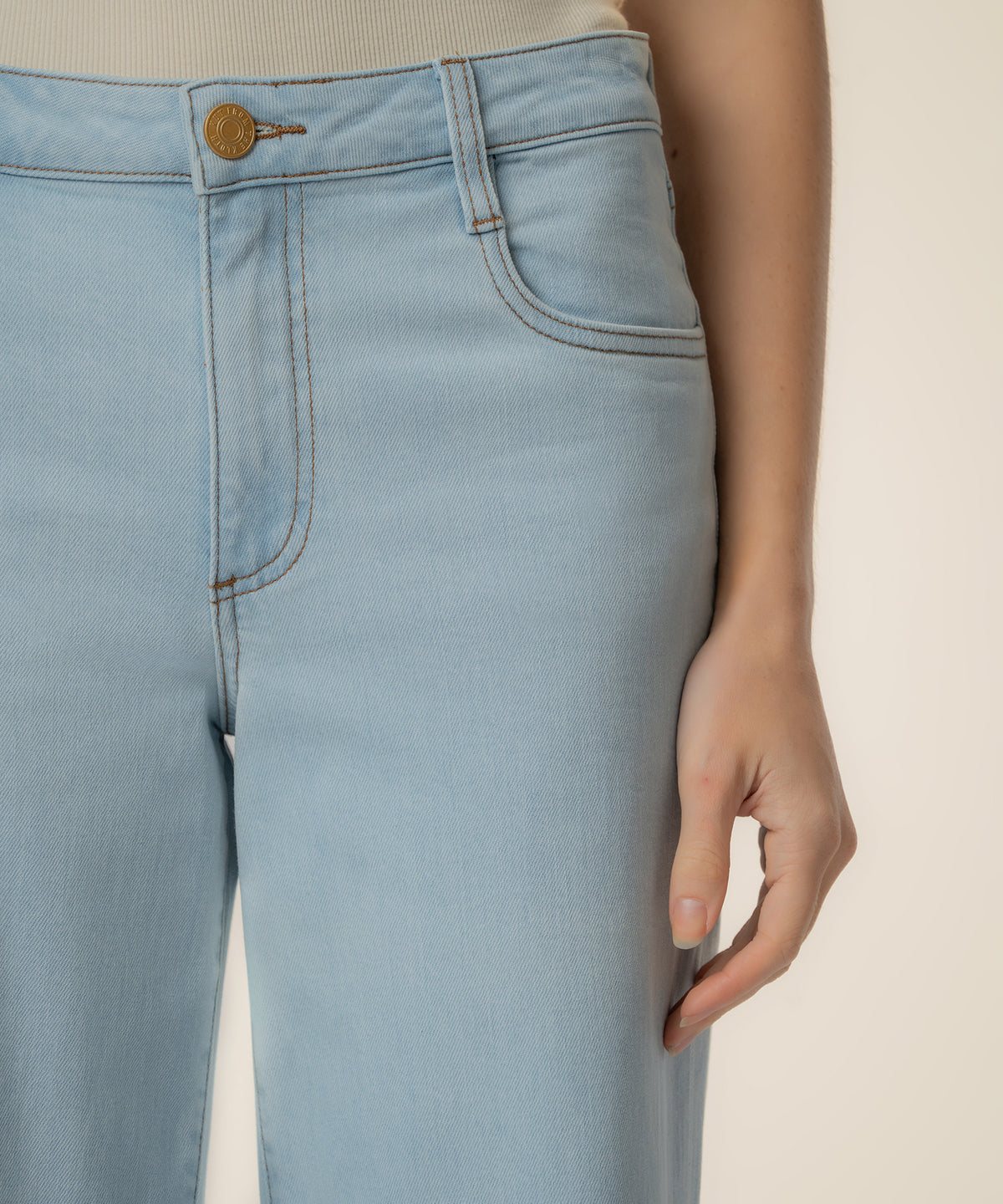 Light blue high-rise wide-leg jeans with gold button and brown stitching detail at waistband.