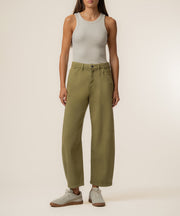 Olive-green high-rise relaxed-leg trouser with wide leg opening worn with white tank top and sneakers.