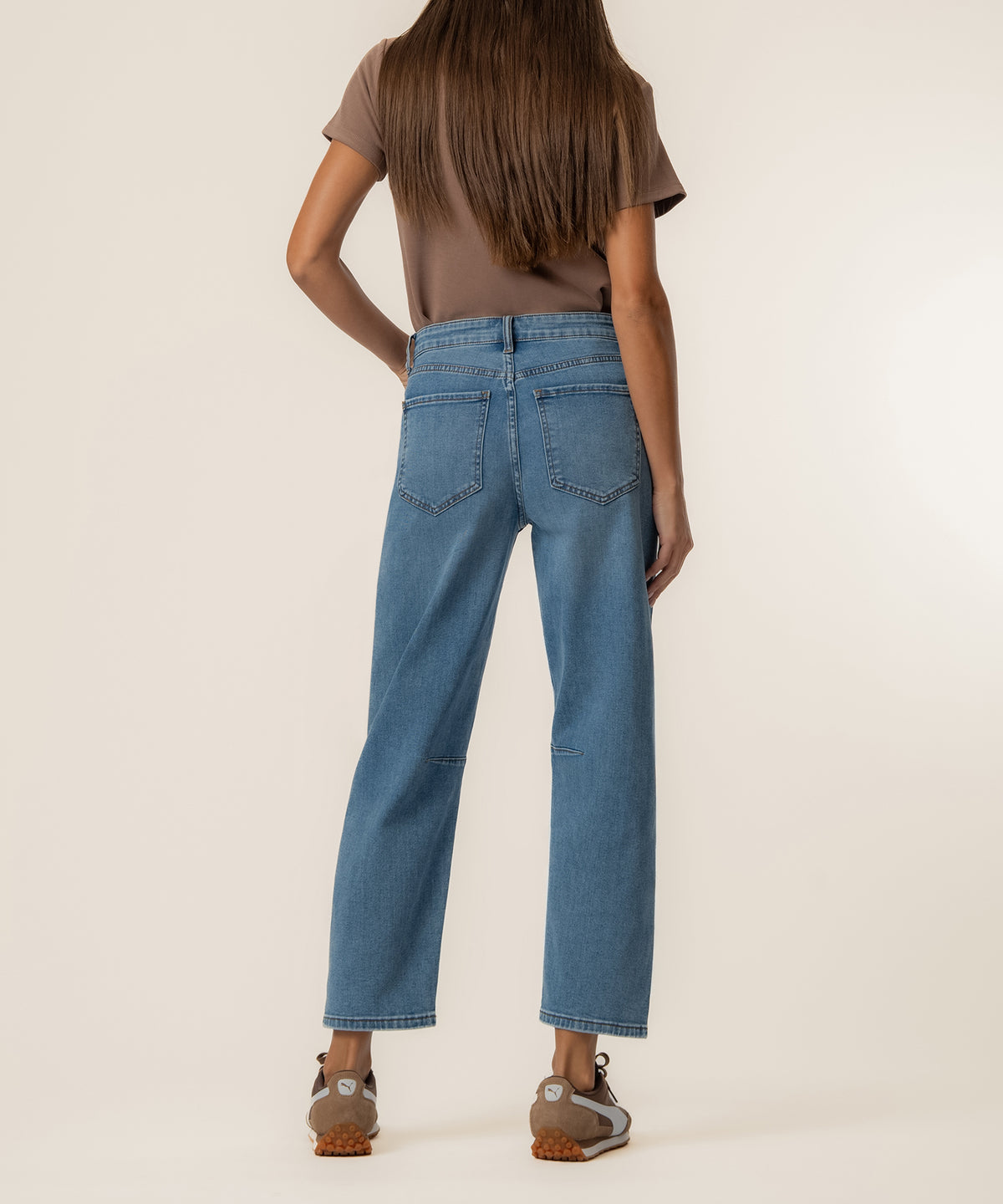 Woman wearing blue high-rise relaxed-leg jeans with medium wash and cropped ankle length, shown from back view.