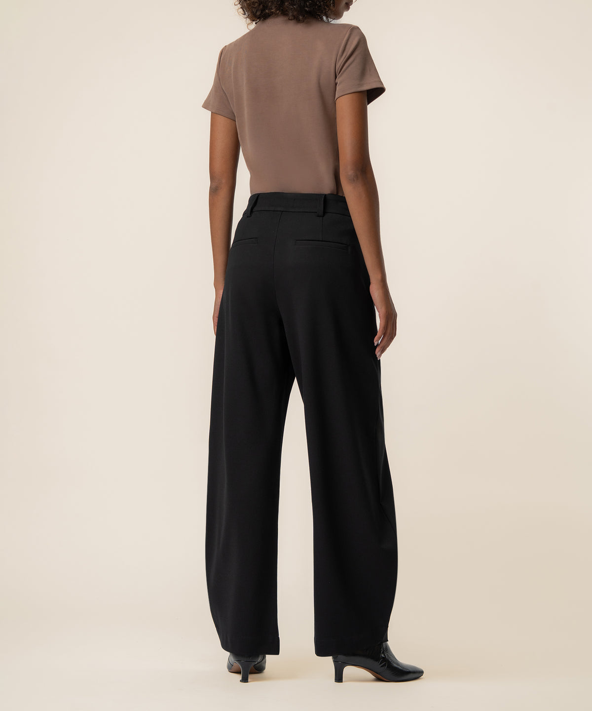 Black high-rise balloon pants with wide legs and tapered ankles, shown from back view on model.