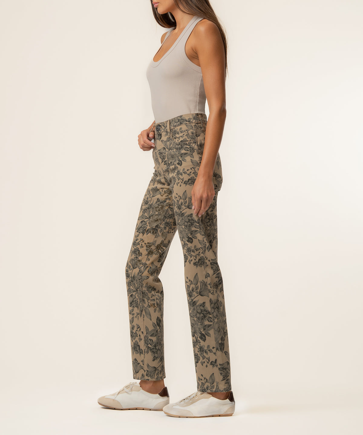 Woman wearing sand-colored high-rise straight-leg pants with dark floral print and white sleeveless tank top.