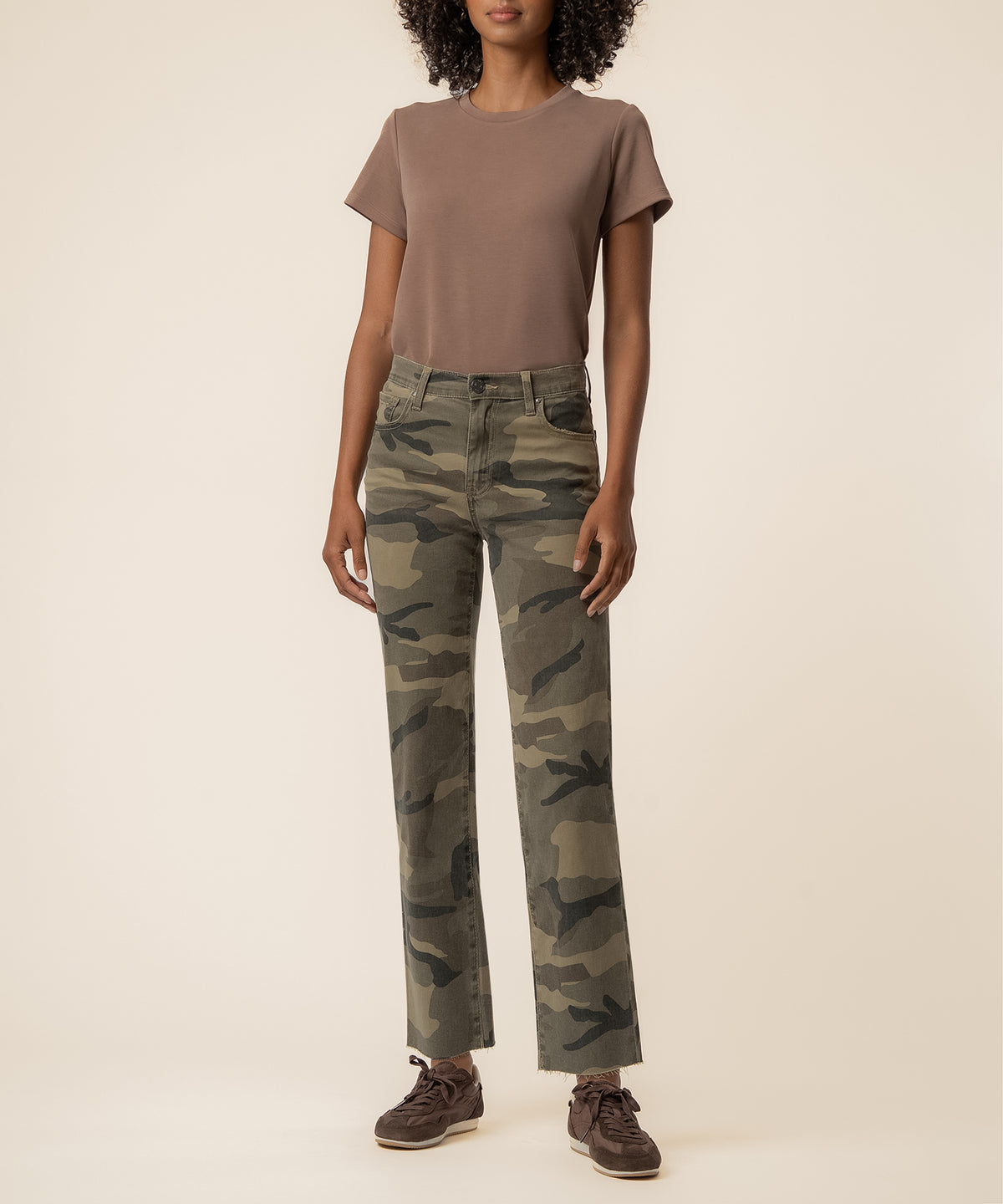 Woman wearing olive camouflage high-rise straight-leg jeans with a brown short-sleeve t-shirt.