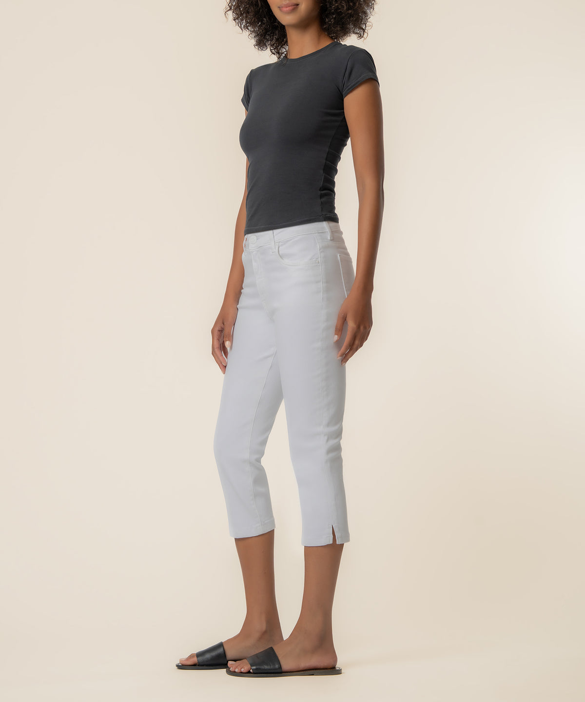 Woman wearing black short-sleeve t-shirt and white high-rise capri pants with side slit hem.