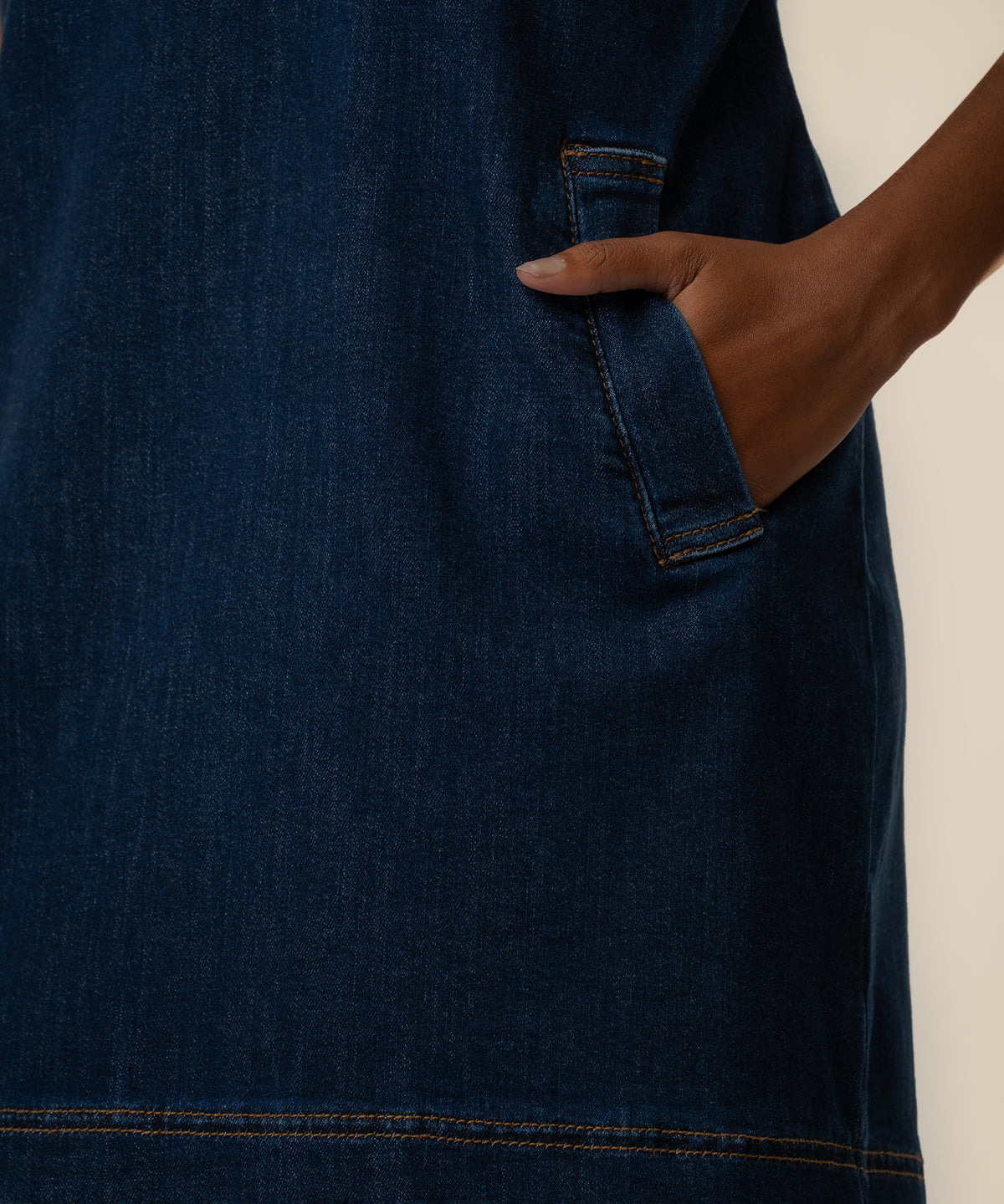 Dark blue denim dress with front patch pockets and visible topstitching detail.