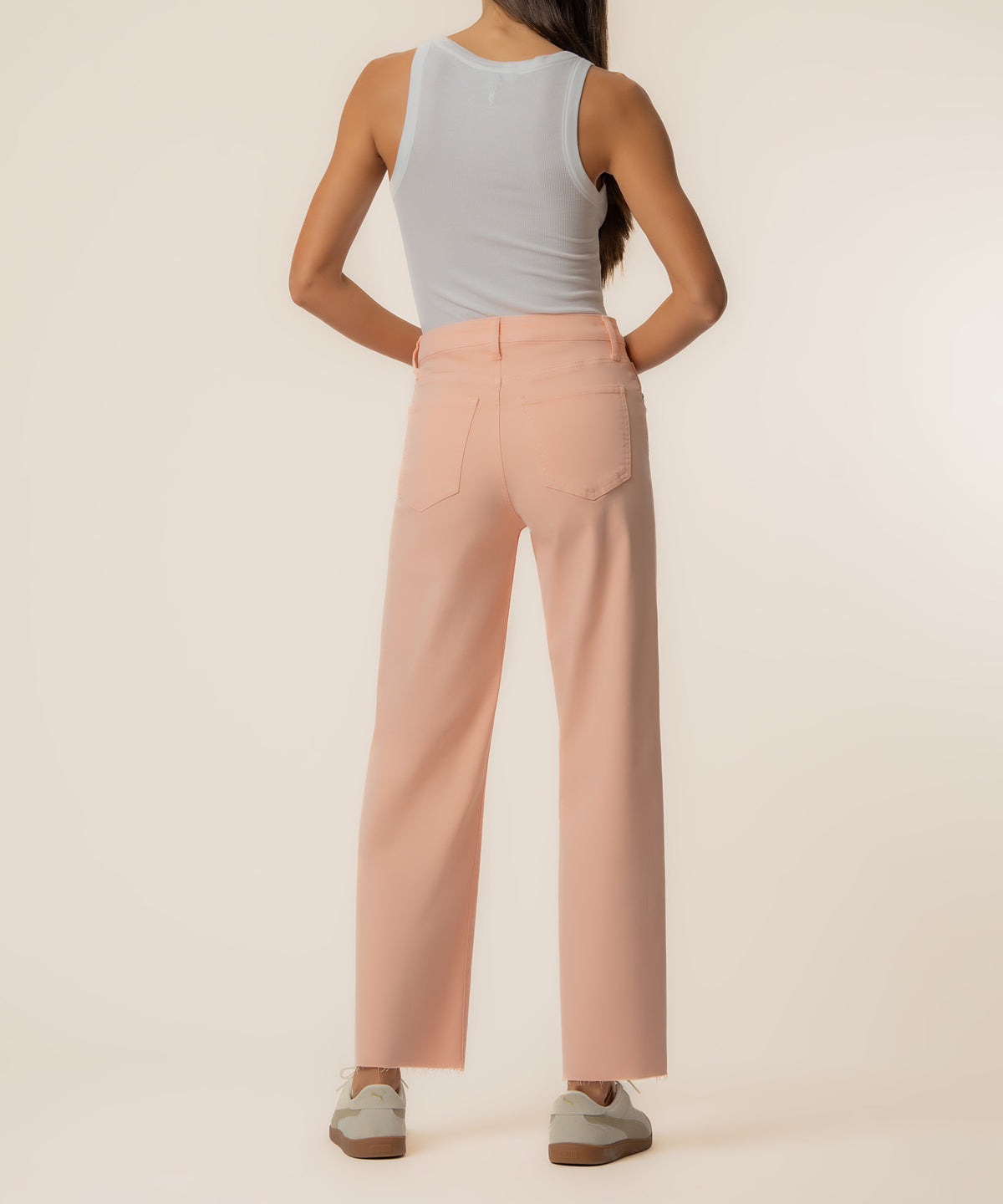 Peach high-rise wide-leg jeans with five-pocket styling on model wearing white tank top.